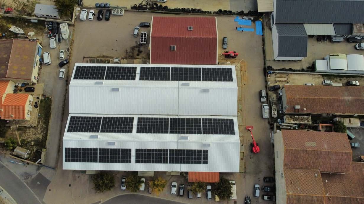 Vue aérienne d'un bâtiment industriel dont la toiture est entièrement couverte de panneaux photovoltaïques